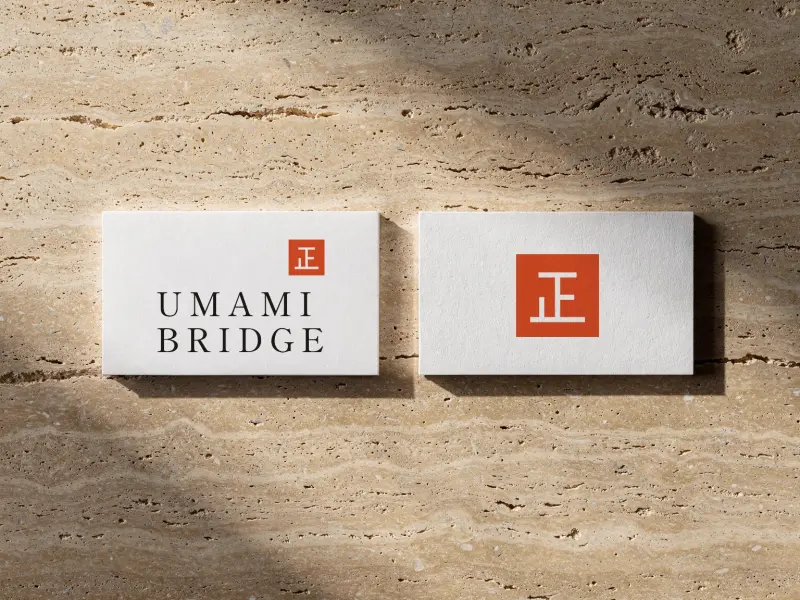 Umami Bridge business cards, front and back, on travertine
